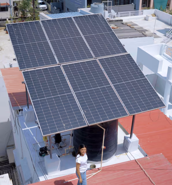 A girl on her roof with solar panels beside her